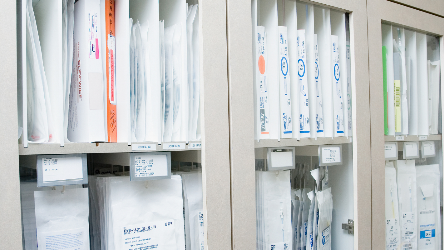 Medical specimen storage cabinets with glass doors, filled with white specimen bags and labeled files.